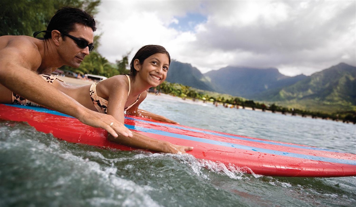 NCL Hawaii two people surfing in front of island