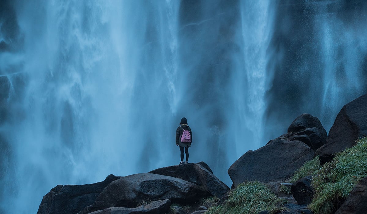 Person standing in front of waterfall 